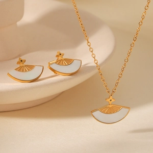 Macro shot of gold fan-shaped white shell pendant necklace and matching stud earrings