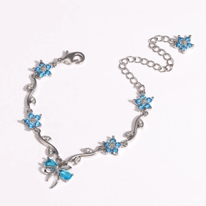 Detail of silver bracelet with blue zircon butterfly and flower charms on white background