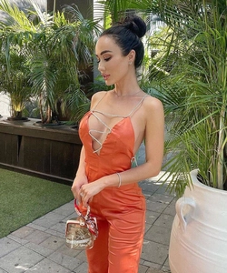 Détail d'une combinaison en satin orange avec chaîne en strass scintillante au cou