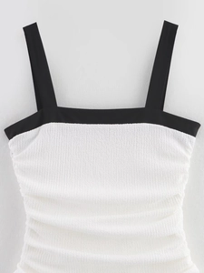 Close-up of black and white contrast dress featuring textured pleated fabric and square neck