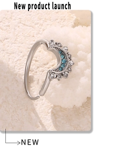 Macro shot of silver crescent ring with zircon stones on white textured stone background
