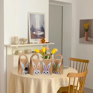 Detail of four kraft paper Easter bunny gift bags with handles on a table