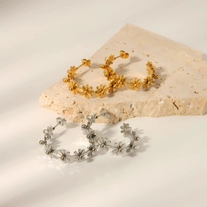 Elegant gold and silver C-shaped floral hoop earrings on textured stone surface