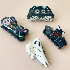 Close-up of Halloween hair claws featuring spider, ghost, skull, and bat designs