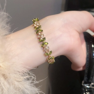Detail of flower bracelet with green marquise zircon stones and gold finish