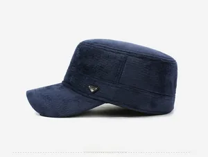 Detail of navy corduroy flat cap featuring a fashion metal triangle badge on side