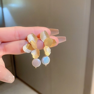 Detailed close-up of golden flower petal earrings with hanging baroque pearls for women