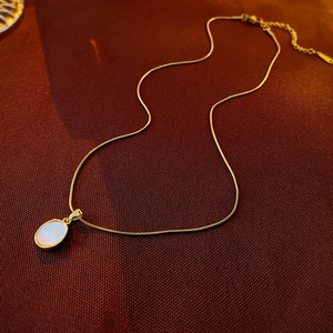 Close-up of a gold snake chain necklace with an iridescent shell inlay oval pendant