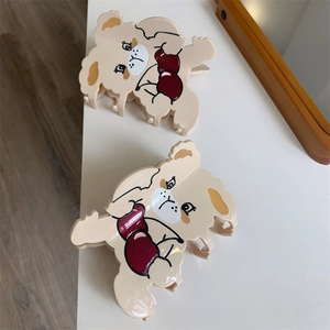 Cute cream puppy hair claw clips with red heart accents on a white surface
