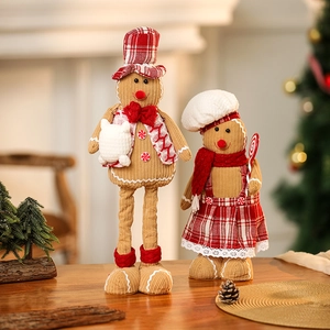 Pair of telescopic gingerbread plush figures with hats on a cozy wooden holiday table