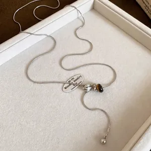Detail of silver snake chain necklace with tiger eye stone and spotted stone beads