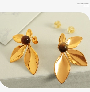 Detail of 18K gold flower earrings featuring natural stone and smooth metallic petals