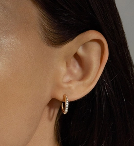 Close-up of elegant gold C-shaped earrings with micro-set cubic zirconia on female model