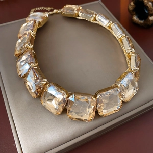 Dettaglio macro della collana d'oro con cristallo champagne su scatola per gioielli