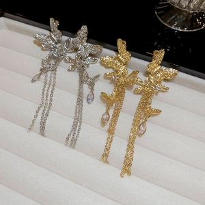 Detailed view of butterfly tassel earrings with metal texture and crystal drops