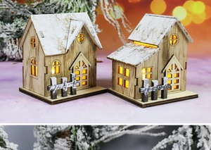 Dettaglio di case natalizie in legno a LED con tetti innevati e luci calde alle finestre.