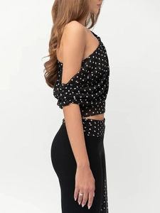 Détail du crop top noir à pois avec design à une épaule et tissu en mousseline plissée