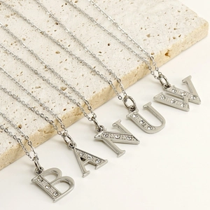 Macro shot of silver letter pendants A, B, N, U, W with rhinestones on stone plate