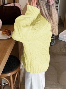 Detailed cable knit pattern on yellow turtleneck sweater showing high-quality texture