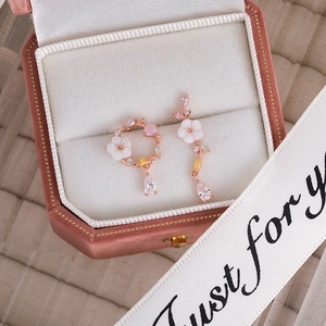 Detailed macro view of pink zircon flower earrings with water drop pendants in a velvet box