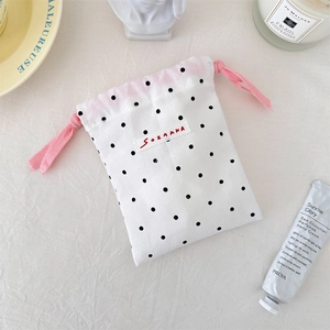 Detailed close-up of polka dot drawstring storage bag with pink rope and canvas texture
