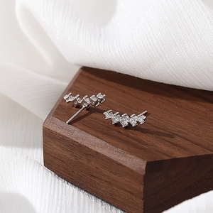 Minimalist S925 silver curved stud earrings with sparkling pavé zircons on a wooden base