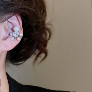 Detail of elegant silver ear cuff with zircon heart and pearls worn on a model's ear