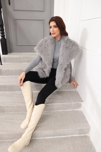 Nahaufnahme einer grauen Webpelzweste mit beigen Lederstiefeln für einen eleganten Winterlook