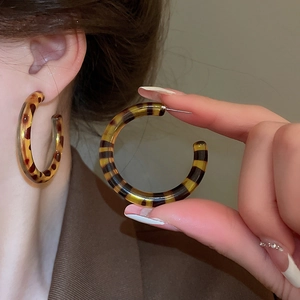 Macro shot of retro leopard print resin hoop earrings with textured amber finish