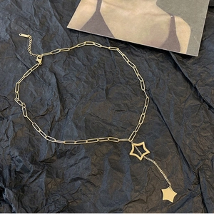 Gold titanium star pendant necklace with hollow star and tassel on paper background