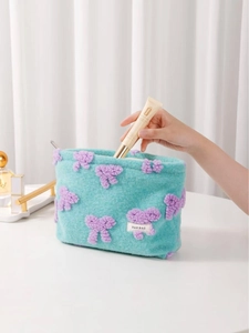 Plush mint green makeup bag with purple bow embroidery and spacious pillow shape