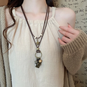 Detail view of retro beaded butterfly pendant necklace with bronze charms and wax cord strap