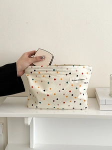 Putting pink makeup cushion into a beige polka dot canvas bag for storage