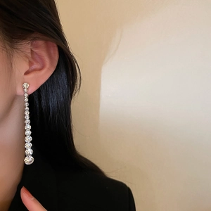 Detail of silver long tassel earrings with sparkling crystals worn by a model