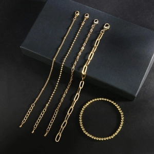 Golden layered bracelet set with butterfly cuban and bead chains on premium black background