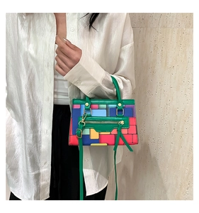 Detail of colorful geometric block pattern handbag with green handle and shoulder strap