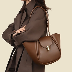 Détail d'un sac à main en cuir marron avec passepoils latéraux et fermoir doré rotatif