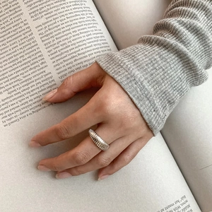 Detailed view of French style 925 sterling silver twill ring on a finger with book backdrop
