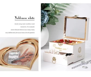 Detail of white vintage jewelry music box with ballerina figure and violin pattern