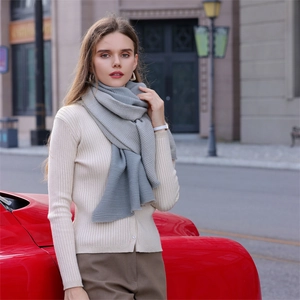 Elegant grey pleated cashmere scarf styled with beige knitwear by a red car