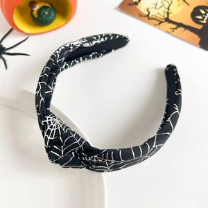 Detail of knot headband with silver spider web patterns and Halloween decorations