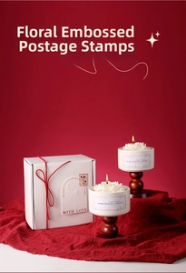 Detail of two floral embossed scented candles in a white gift box with red ribbons