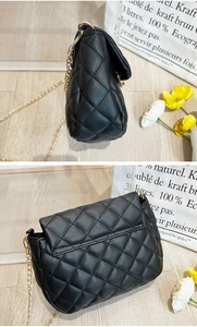 Detail view of black quilted crossbody bag with gold chain strap and back pocket