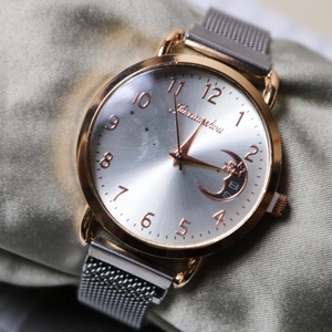 Macro detail of rose gold bezel with moon charm and silver mesh strap watch