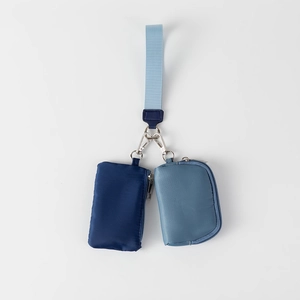 Detail view of dual nylon mini pouches in blue shades with metal clip on fabric lanyard