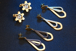 Detailed view of gold flower pearl earrings and metallic teardrop dangle styles