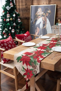 Detailed view of beige Christmas table runner with red poinsettia pattern and tassels