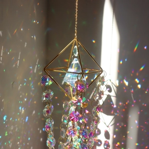 Crystal suncatcher prism with golden geometric frame and rainbow light reflections