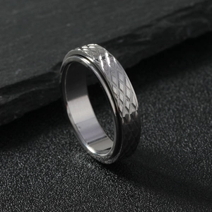 Macro shot of silver 6mm rotatable ring with diamond pattern on black stone surface