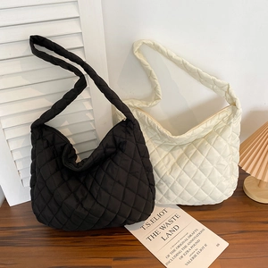 Quilted crossbody cloud bags in black and beige on wooden surface with soft lighting